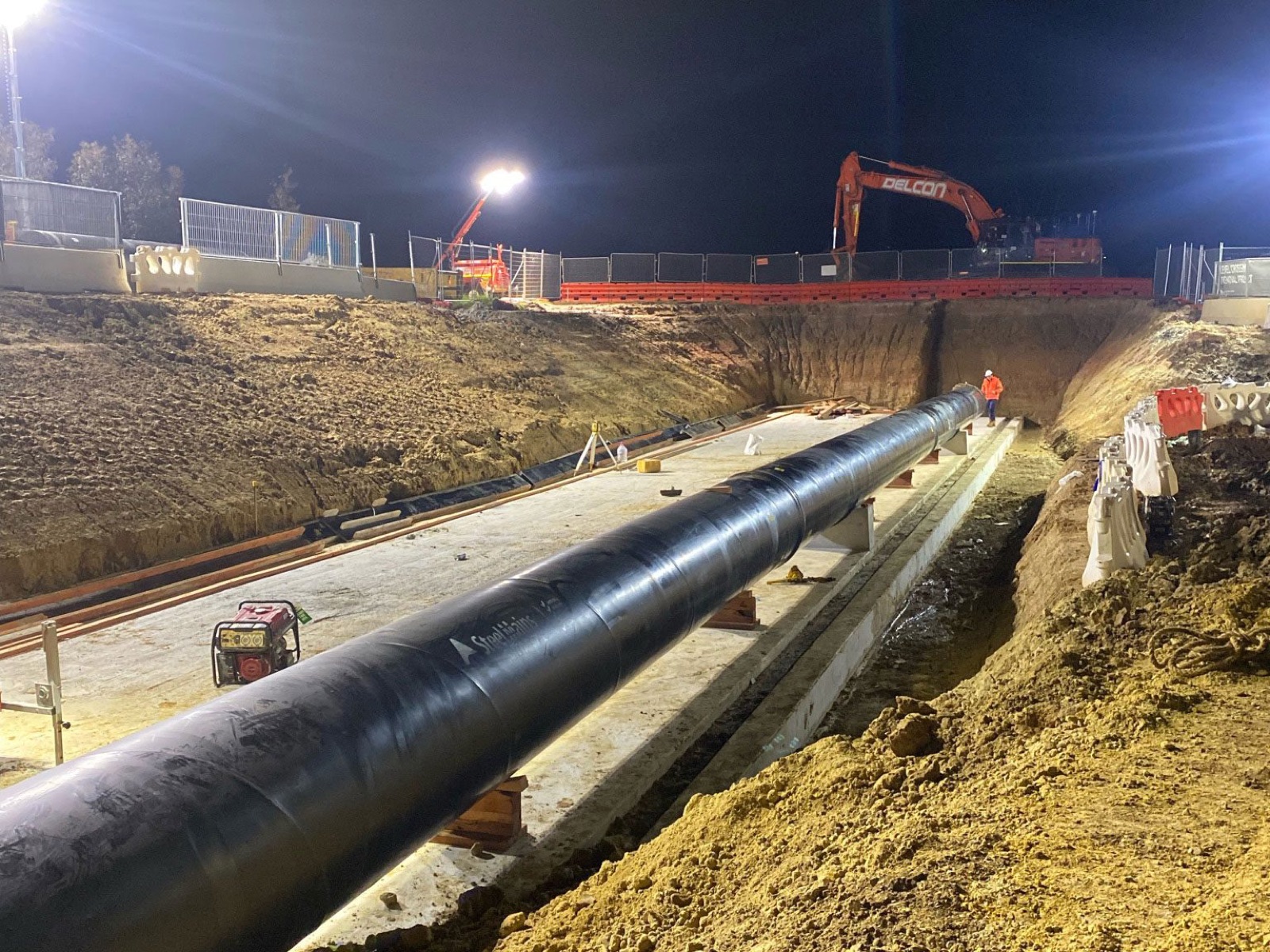 Night works on a major pipeline trench with excavator and crew