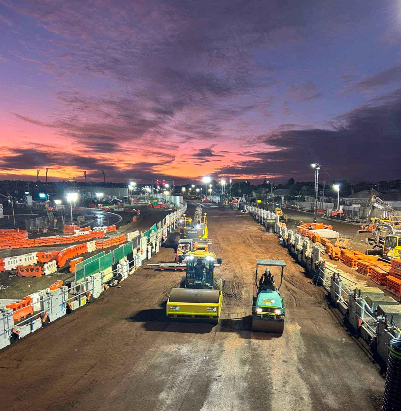 Rollers compacting a rail corridor at dusk on a major Victorian project