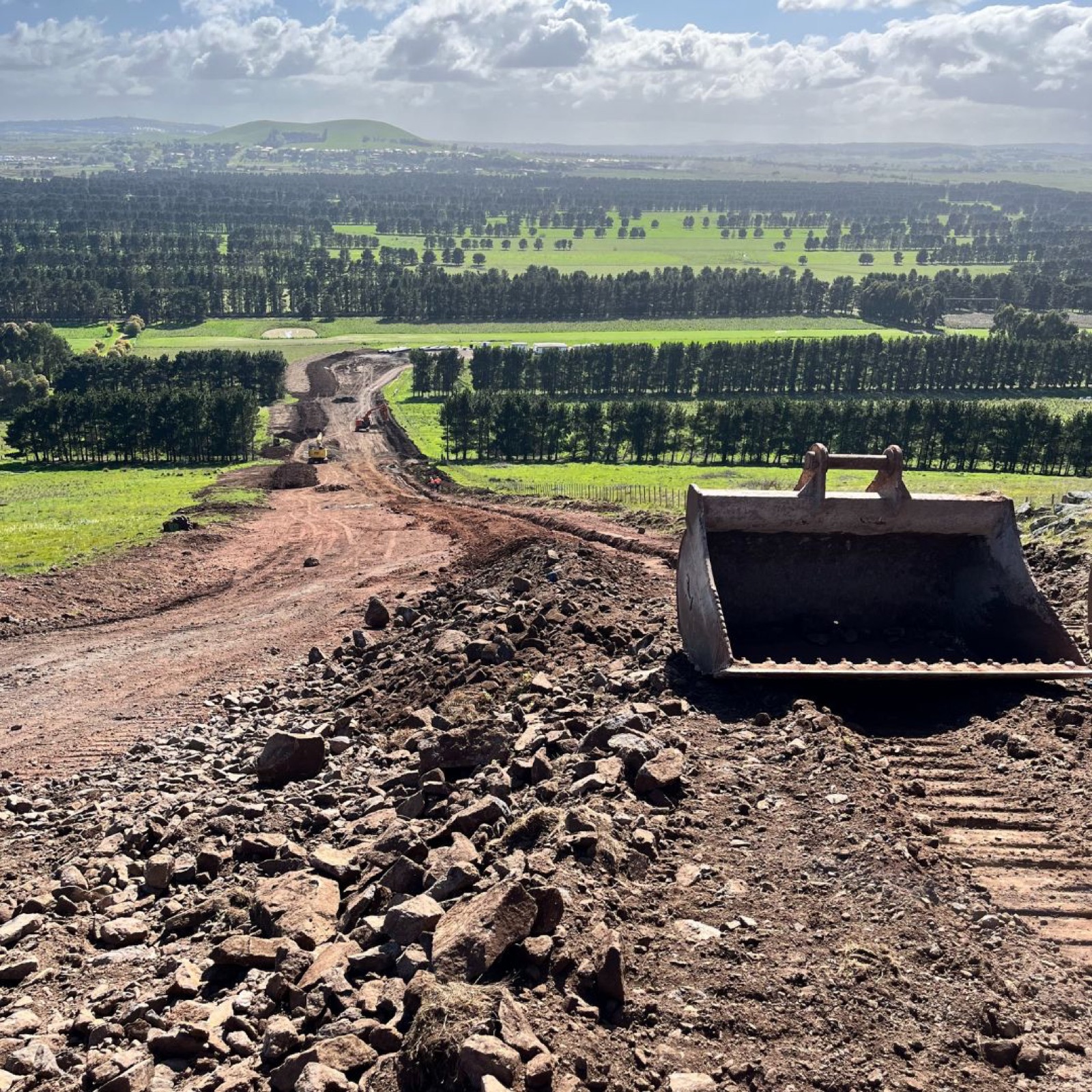 Excavator bucket on a haul road cut through regional Victorian farmland