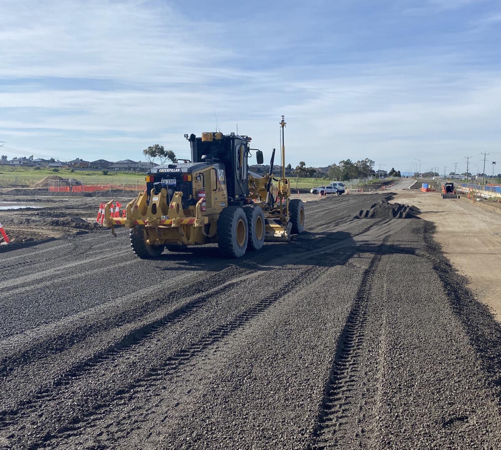 Grader spreading crushed rock pavement on a new road alignment